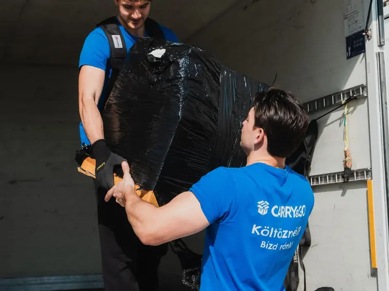 Fóliázott bútor átadása a teherautó rakterébe